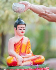 Hand pouring water over Buddha statue in traditional ceremony, Battambang, Cambodia.